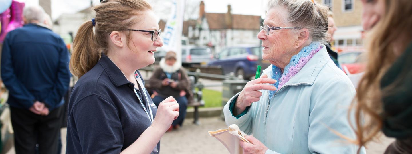 Young Healthwatch volunteer speaking outside to an elderly woman