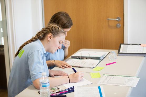 Two young girls sitting at a desk filling in forms